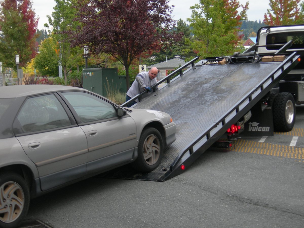A vehicle being positioned on a flatbed tow truck